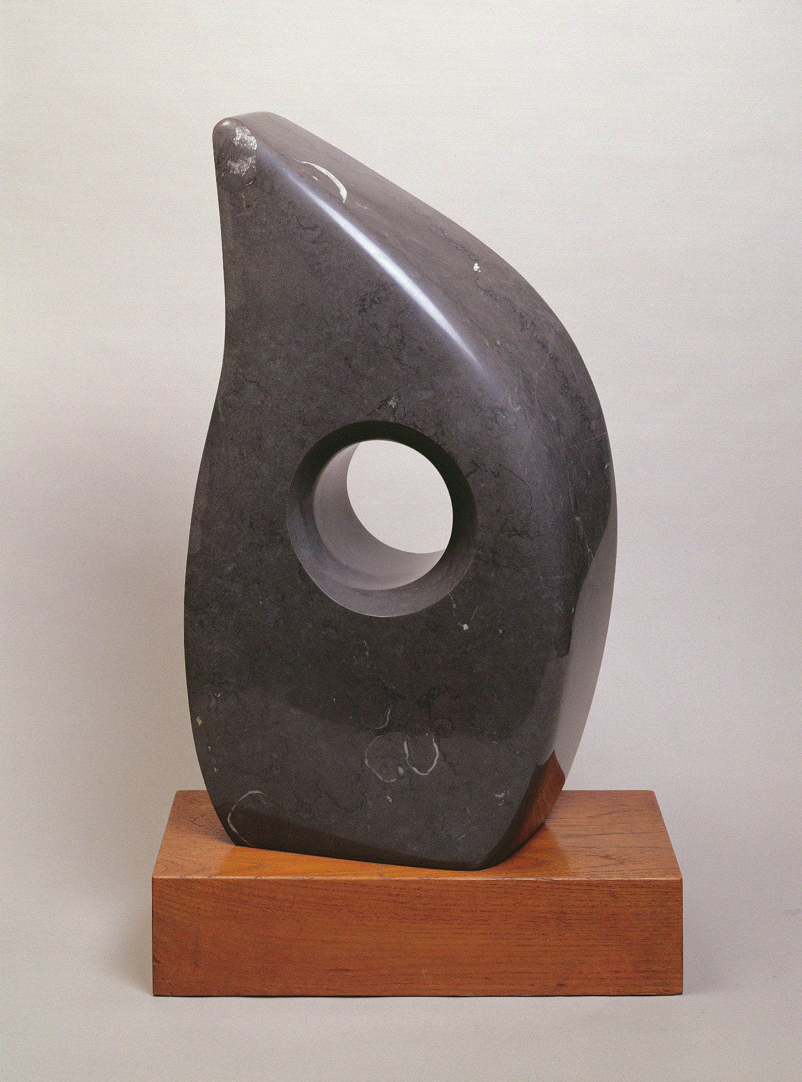 A black marble sculpture in the spae of a tear drop with a hole in its centre.