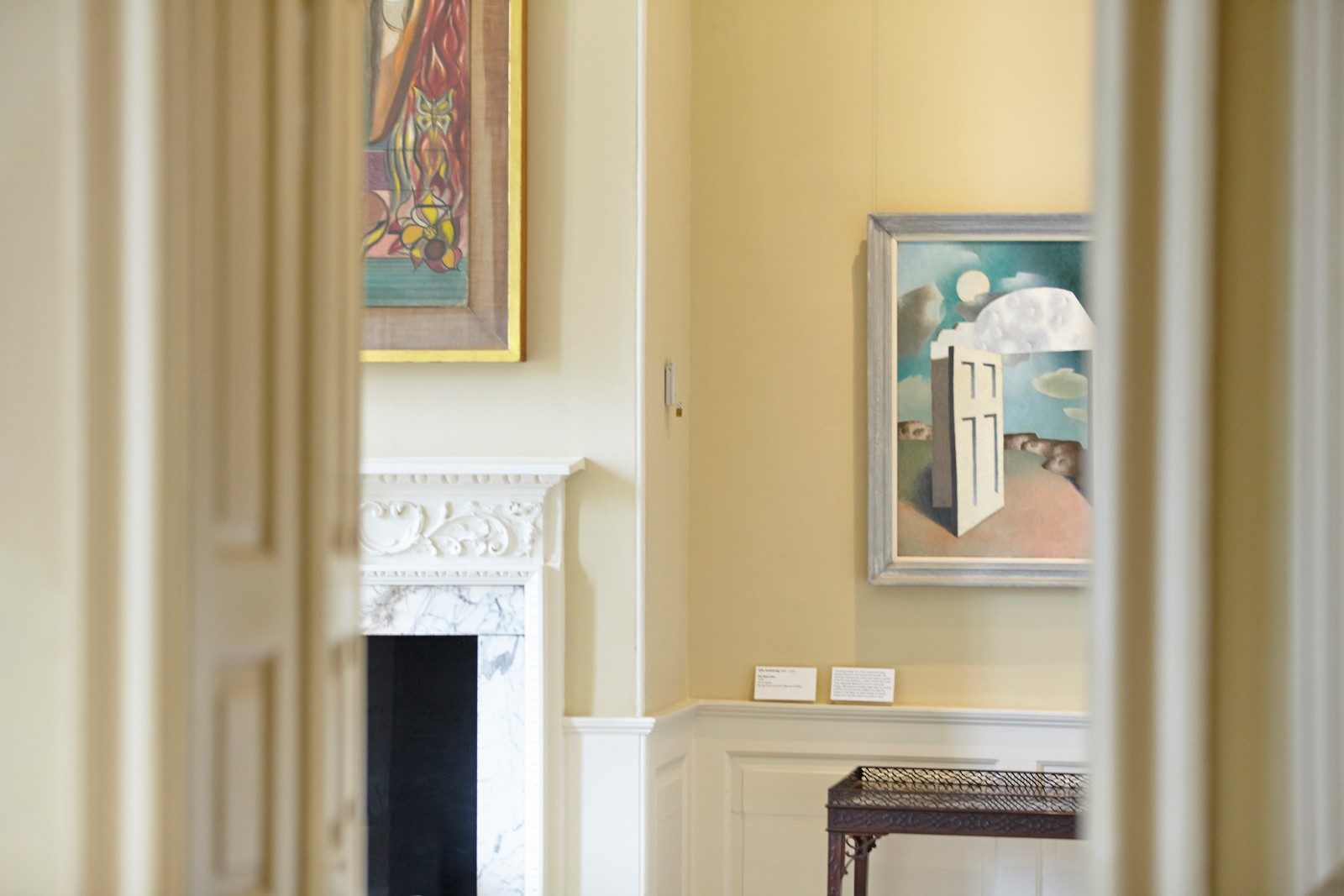 An interior view of a period house looking through a doorway into a room hung with modern art.